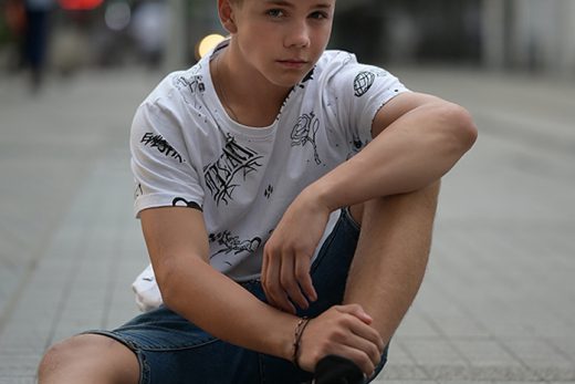 Cool blond boy is sitting on the ground